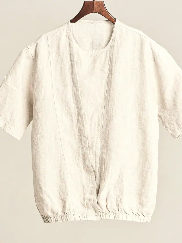 The Camp Shirt in undyed washed linen, laid flat on grey pattern paper.