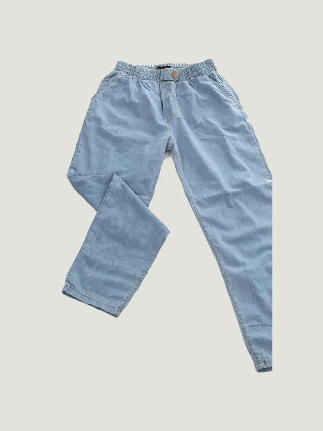 The Carpenter Trouser in pale indigo cotton chambray, laid flat on grey pattern paper.