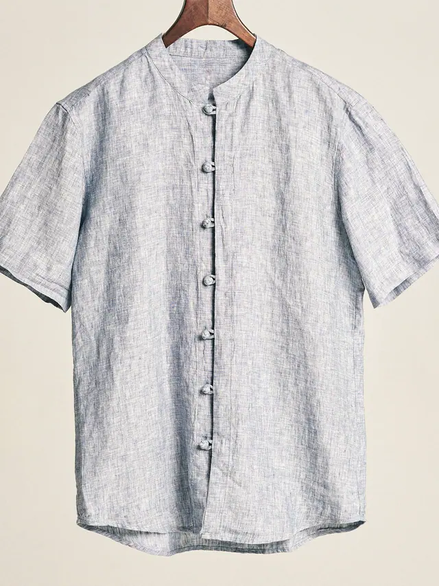 The Chambray Shirt in indigo marl yarn-dyed linen chambray, laid flat on grey pattern paper.