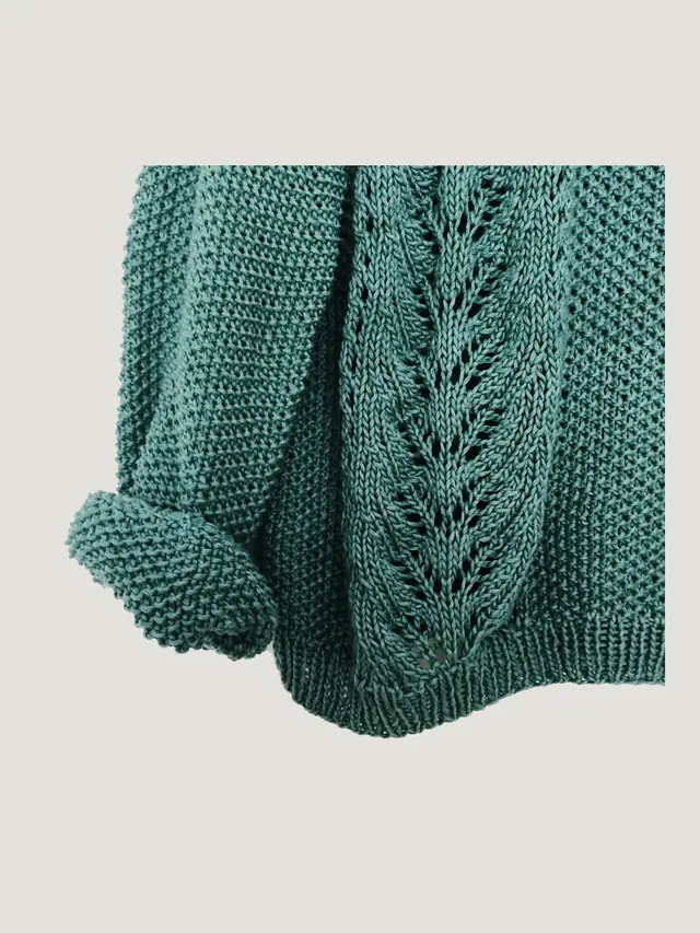 The Crew Knit in verdigris cotton–linen, 12 gauge, laid flat on grey pattern paper.