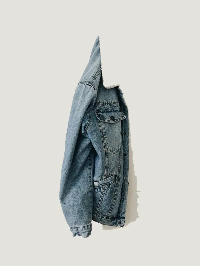 The Denim Overshirt in washed indigo selvedge denim, laid flat on grey pattern paper.